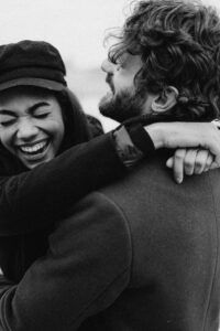 Black and white image of a joyful couple embracing and laughing, capturing a loving moment.