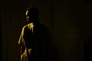 Silhouetted adult man standing indoors, embodying introspection and solitude at night.