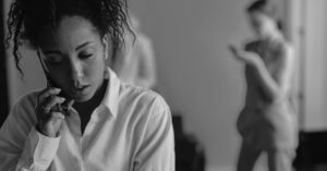 Black and white portrait of a woman talking on the phone with background figures.