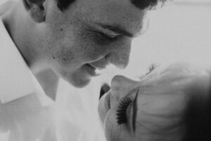 Close-up black and white portrait of a loving couple smiling at each other.