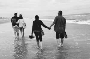 Communication in Sexual Relationships: The Key to Connection and Intimacy Two couples holding hands and walking on a sandy beach with gentle waves.